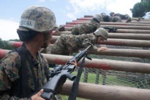 A recruit hands her fellow recruits weapons on an obstacle during the Crucible at the combat training area on Parris Island, S.C. The 54-hour culminating event is designed to emphasize teamwork and adherence to the Marine Corps’ core values under arduous and stressful conditions.(Photo by Lance Cpl. MaryAnn Hill)